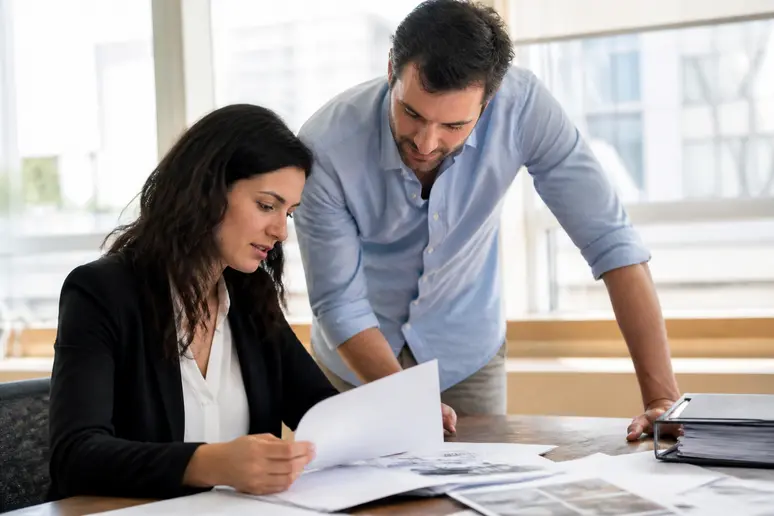 Professionnel analysant des tableaux de données sur papier avant de choisir un crm exemple.