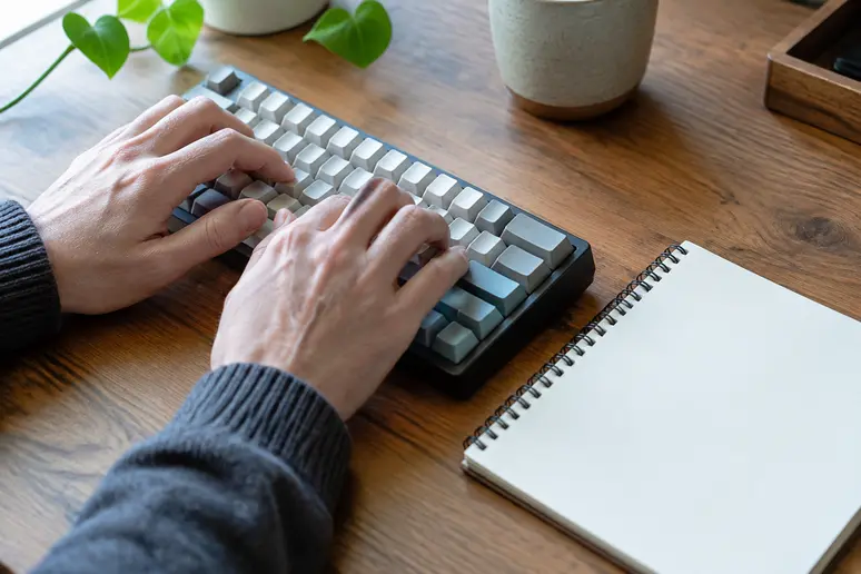 Mains d'un rédacteur écrivant une définition newsletter sur un carnet de notes.