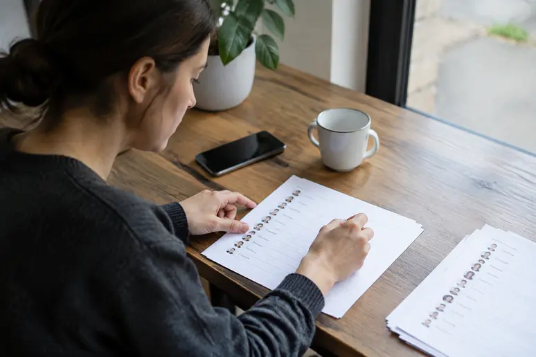 Personne triant des contacts professionnels sur un document papier pour respecter le cadre de la CNIL