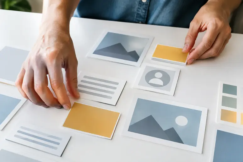 Mains manipulant des blocs de contenu pour structurer un modèle newsletter sur un plan de travail