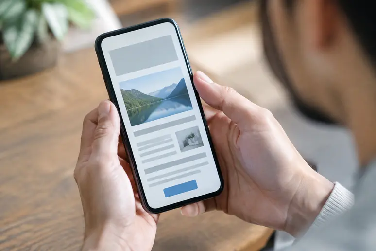 Personne vérifiant l'affichage responsive d'une newsletter sur smartphone en conditions réelles