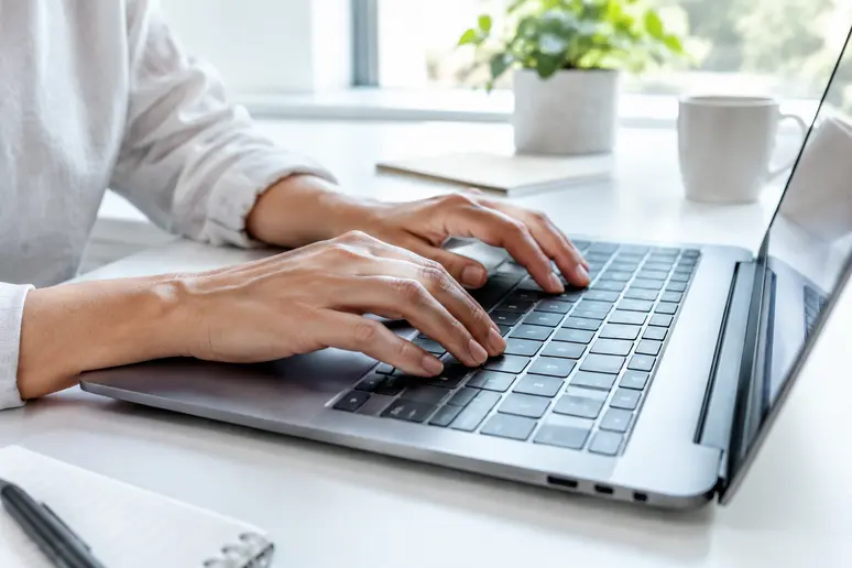 Mains d'un rédacteur tapant un objet court pour rédiger une newsletter efficace.