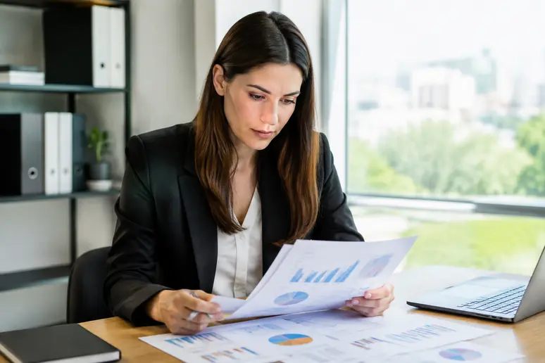 Professionnel analysant les indicateurs de performance et le taux de conversion emailing sur des rapports imprimés