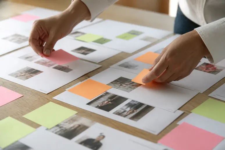 Mains triant des notes de veille et des mentions d'entreprise sur un bureau