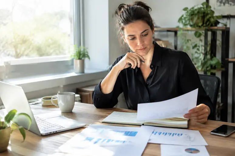Professionnel consultant ses notes de stratégie pour configurer son logiciel de newsletter au bureau